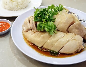 Delicious Singaporean Hainanese chicken rice with tender poached chicken, herbs, and flavorful sauce.